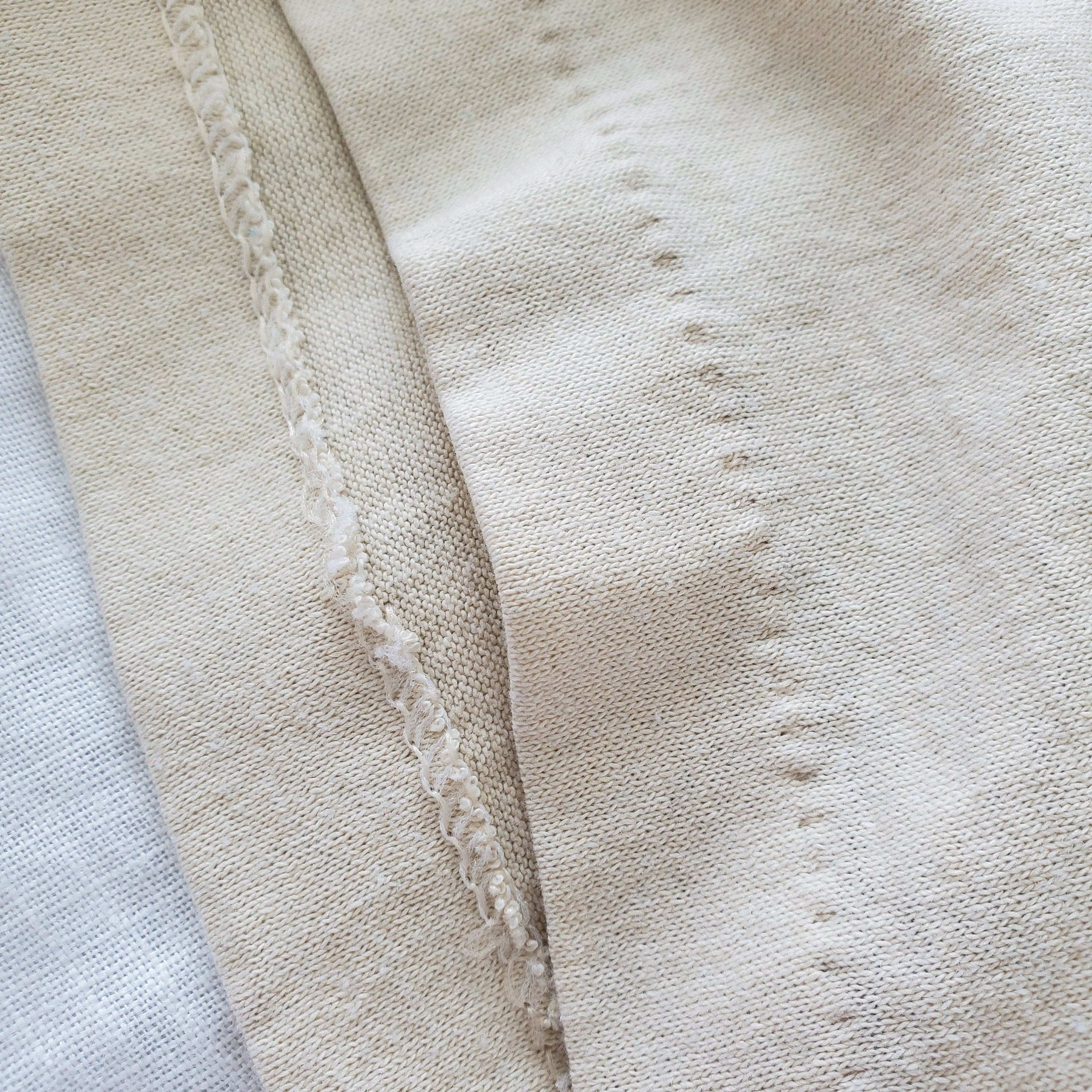 Close-up of a single-stitch hem on a vintage t-shirt showing one line of thread