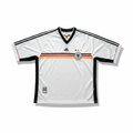 A white Adidas Germany national team soccer jersey with black shoulder stripes, a black V-neck collar, and a horizontal black, red, and yellow stripe across the chest. The jersey features the Adidas logo on the right chest, the German Football Association crest on the left chest, and a small FIFA patch on the lower left hem.